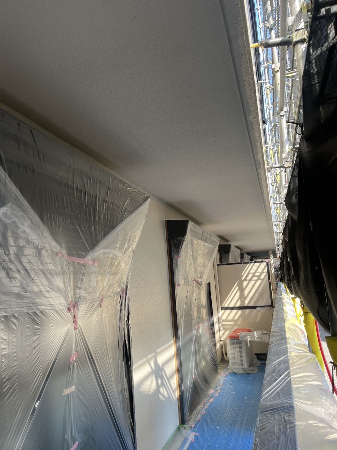 マンションベランダ側の養生作業の様子。サッシや床に丁寧にビニールが施されている。