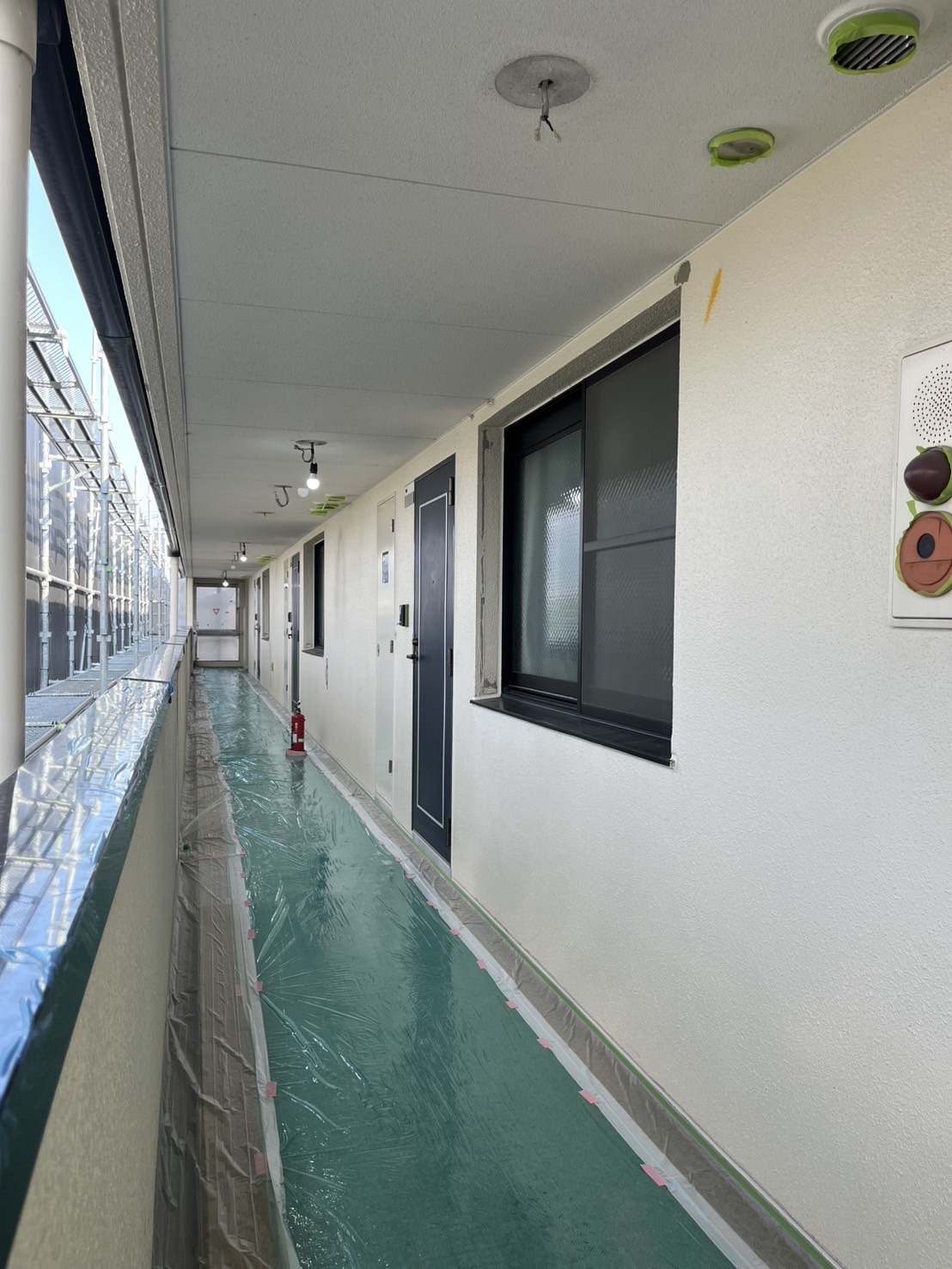 マンション共用廊下側の養生作業。通路やドア周辺がしっかりとマスキングされている。