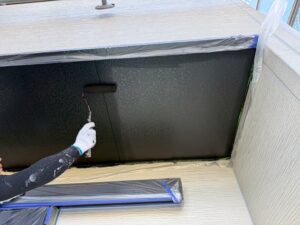 東近江市Y様邸 軒天塗装中。黒系の塗料をローラーで均一に塗り上げる職人の手元